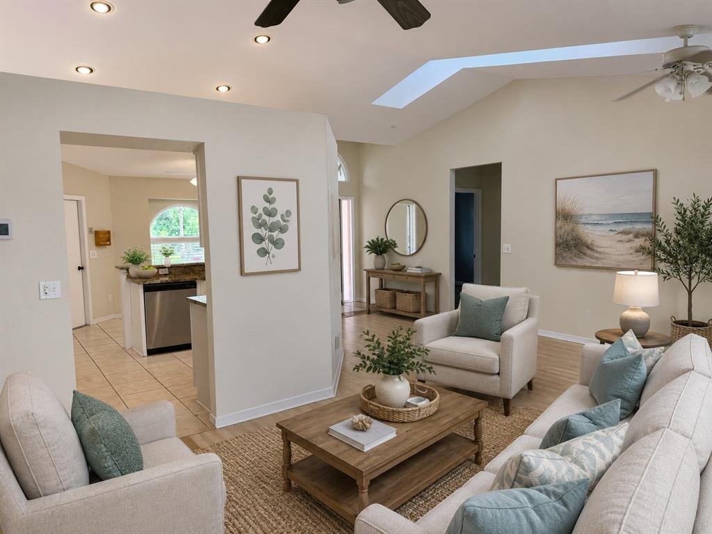 A living room with light-colored furniture, a wooden coffee table, and a view into the kitchen — 3670 LAKE BOULEVARD, CLEARWATER, FL