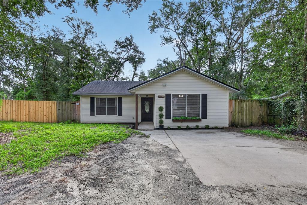 A single-story house with light siding, black shutters, and a concrete driveway sits outdoors — 30832 RIDGEVIEW AVENUE, MOUNT PLYMOUTH, FL
