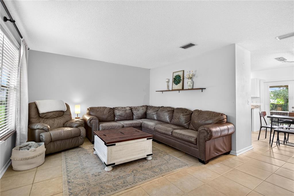 A living room features a brown leather sectional, a recliner, and a white coffee table — 30832 RIDGEVIEW AVENUE, MOUNT PLYMOUTH, FL