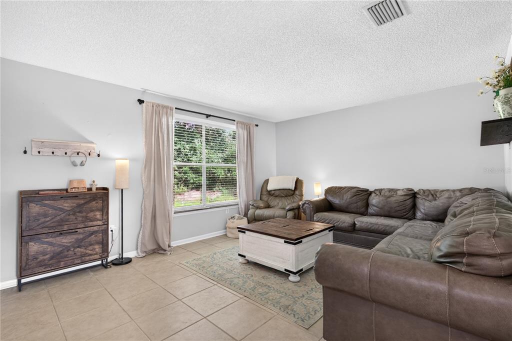 A living room features tile flooring, a brown sectional sofa, and a white coffee table — 30832 RIDGEVIEW AVENUE, MOUNT PLYMOUTH, FL
