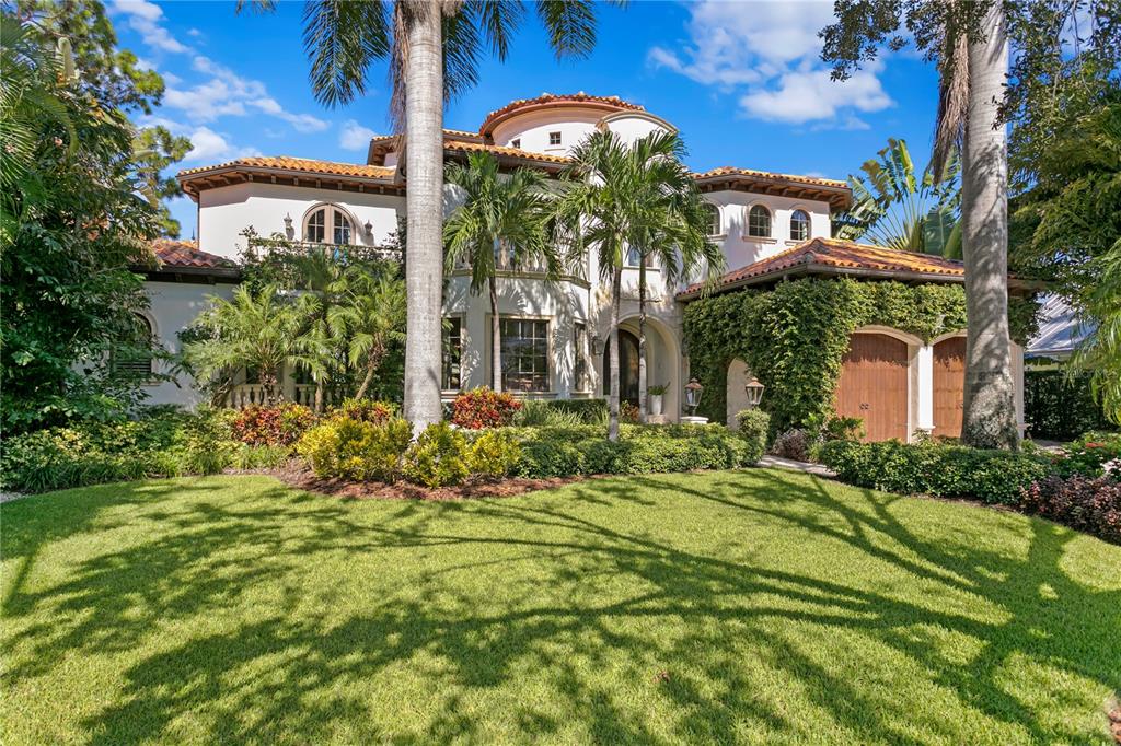 A two-story Mediterranean-style house with a tile roof, arched windows, and lush landscaping — 25 W SPANISH MAIN STREET, TAMPA, FL