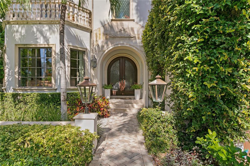 A stone walkway leads to an arched wooden double door entrance of a stucco home — 25 W SPANISH MAIN STREET, TAMPA, FL