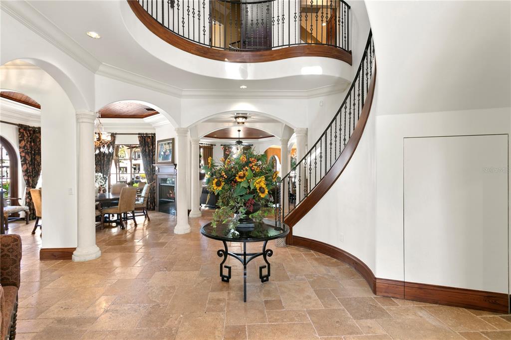 A grand foyer features a curved staircase, tile flooring, and a central pedestal table — 25 W SPANISH MAIN STREET, TAMPA, FL