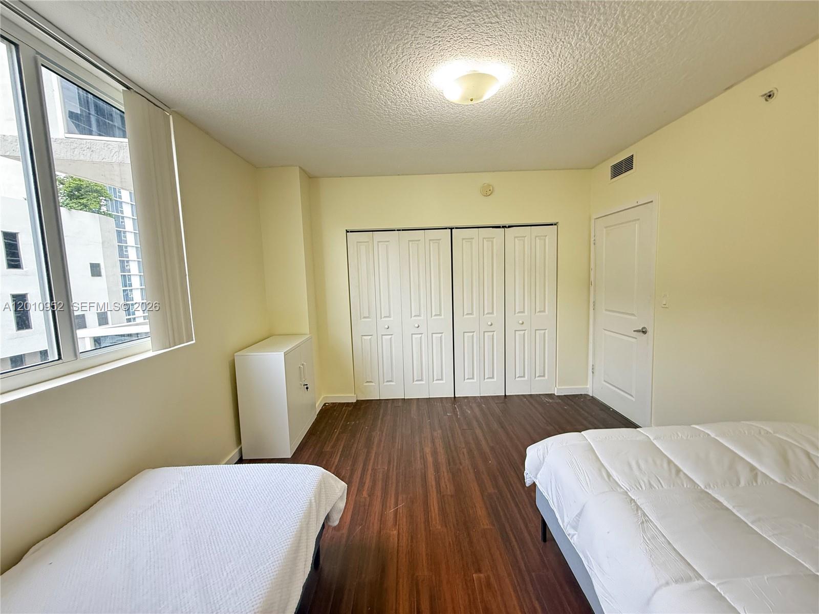 A bedroom with wood-look flooring, white closet doors, a white cabinet, and two beds — 601 NE 23rd St # 901, Miami FL 33137, MIAMI, FL
