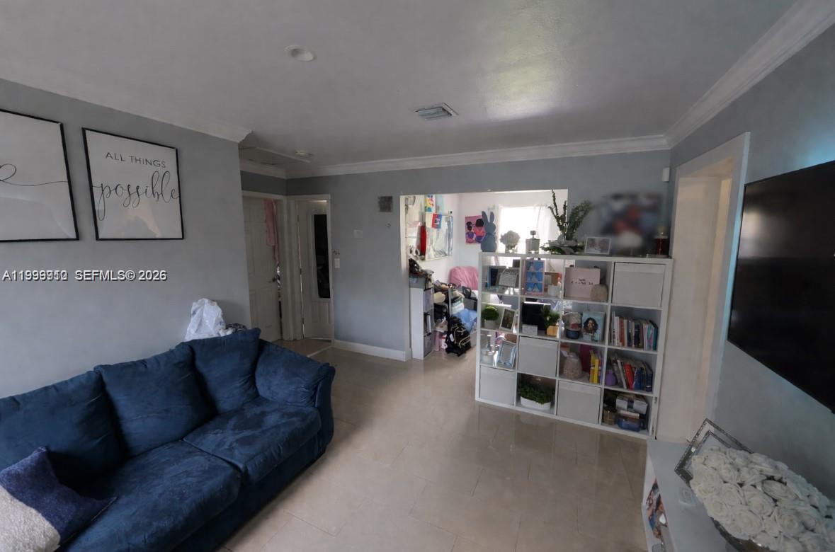 A living room features a blue sofa, a white cube storage unit, and wall art — 442 NE 162nd St, Miami FL 33162, MIAMI, FL