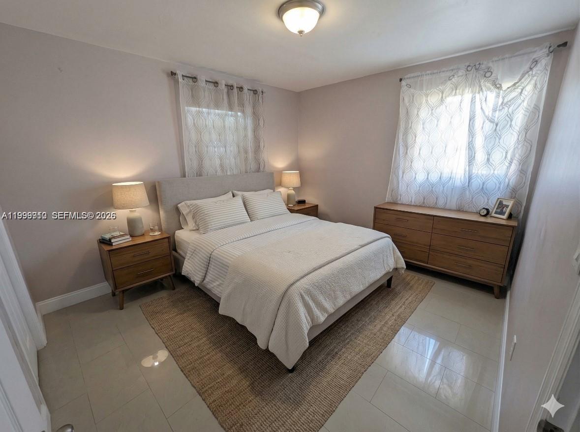 A bedroom features a bed with a light-colored headboard, two nightstands, and a wooden dresser — 442 NE 162nd St, Miami FL 33162, MIAMI, FL