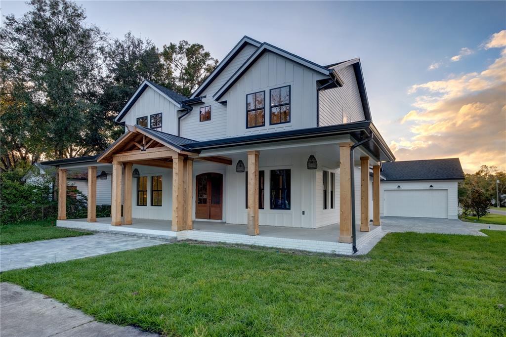 A two-story white farmhouse with a large covered porch, wooden pillars, and a detached garage — 805 W INDIANA AVENUE, TAMPA, FL