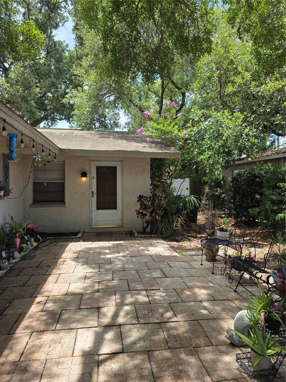 A paved patio leads to the entrance of a single-story home with a brown door — 3074 PINE TREE AVENUE UNIT B, LARGO, FL