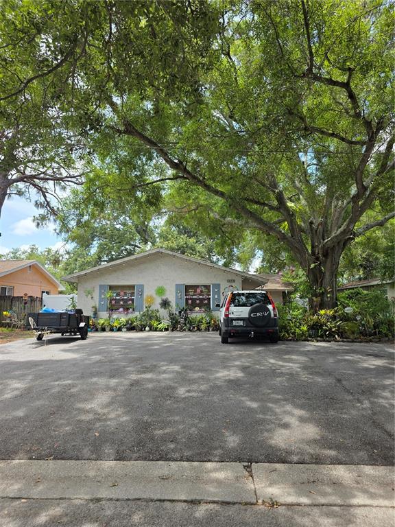 A single-story house with a large paved driveway, a parked SUV, and a utility trailer — 3074 PINE TREE AVENUE UNIT B, LARGO, FL