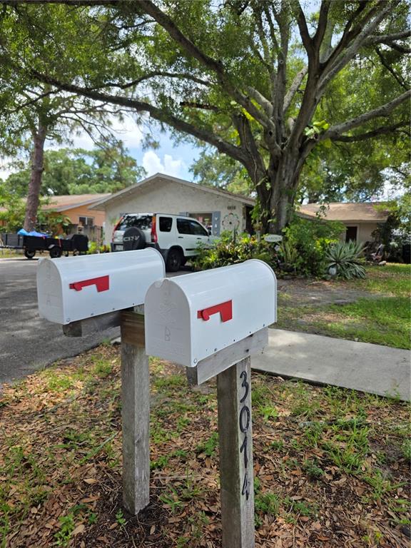 Two white mailboxes stand on wooden posts in front of a house and a tree — 3074 PINE TREE AVENUE UNIT B, LARGO, FL