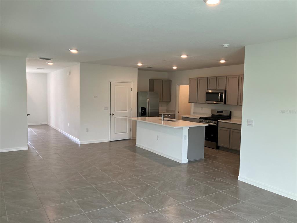 A kitchen with gray cabinets, stainless steel appliances, and a white island with a sink — 35694 KINSEY POINT, ZEPHYRHILLS, FL