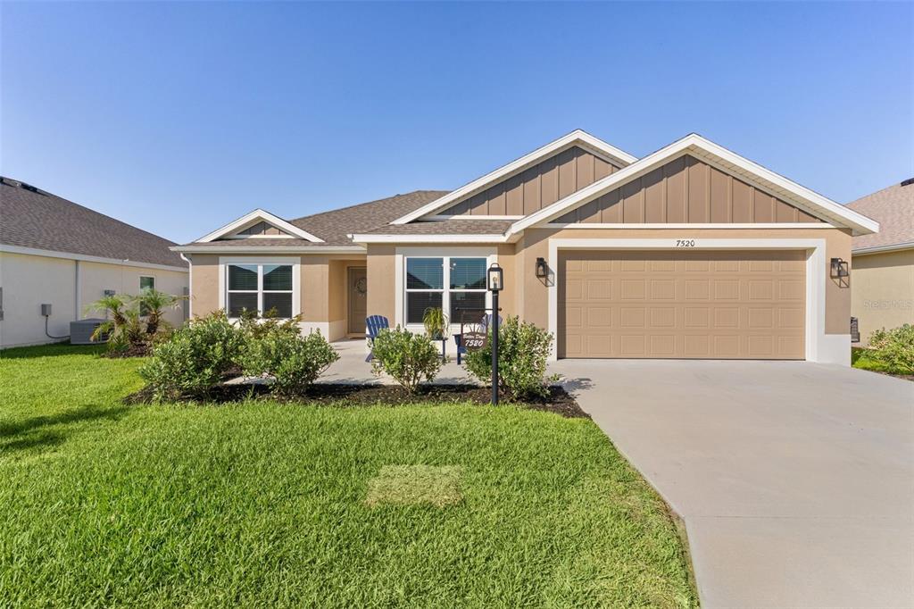 A single-story suburban house with a tan stucco exterior, brown gabled roof, and two-car garage — 7520 FAR HILLS LOOP, THE VILLAGES, FL