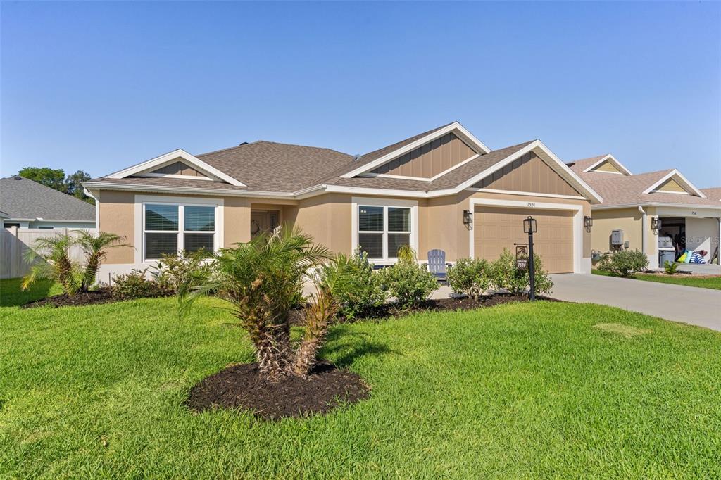 A single-story suburban house with a tan stucco exterior, brown roof, and a two-car garage — 7520 FAR HILLS LOOP, THE VILLAGES, FL