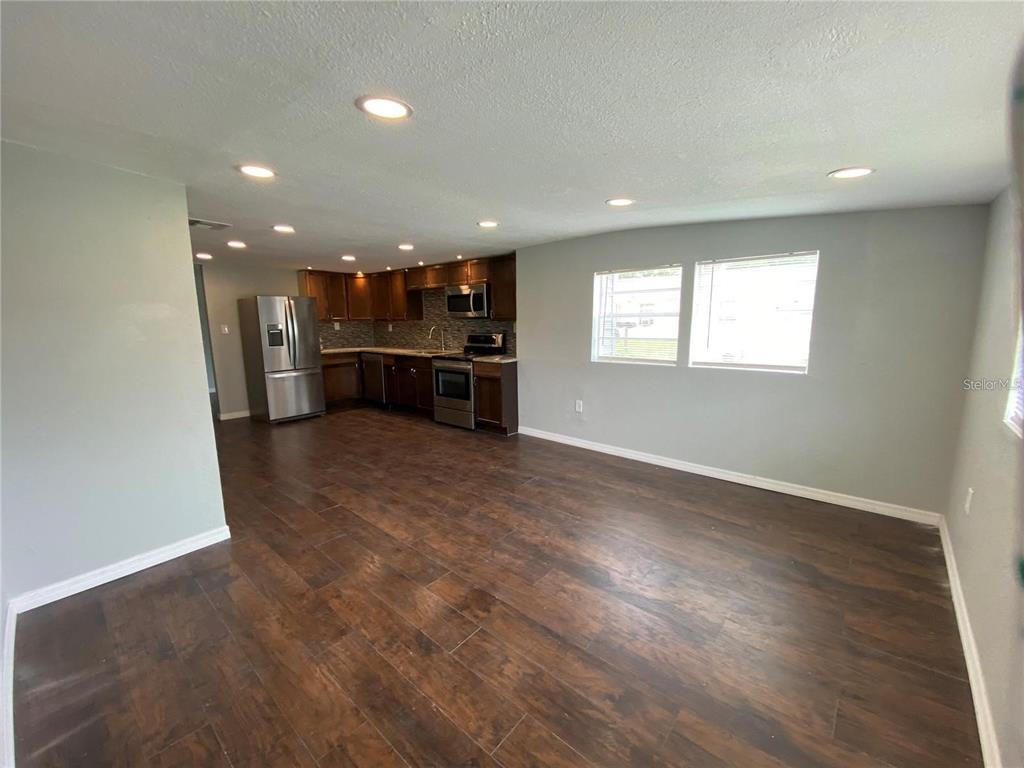 An open-concept kitchen and living area features dark wood-look flooring and recessed lighting — 306 PALMETTO AVENUE NW, WINTER HAVEN, FL