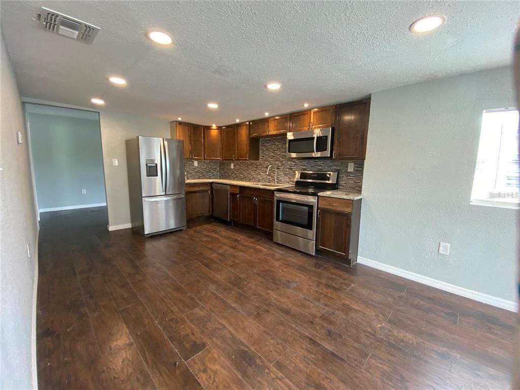 A kitchen features dark wood cabinets, stainless steel appliances, and wood-look flooring — 306 PALMETTO AVENUE NW, WINTER HAVEN, FL