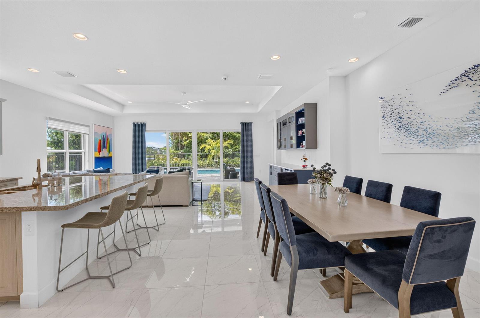 A bright open-concept dining and kitchen area with tile floors, a pool view, and seating — 13197 Whistler Mountain Road, Delray Beach FL 33446, DELRAY BEACH, FL