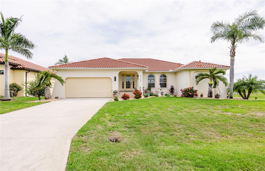 A single-story house with a tile roof, beige stucco exterior, and a two-car garage — 24102 SANTA INEZ ROAD, PUNTA GORDA, FL