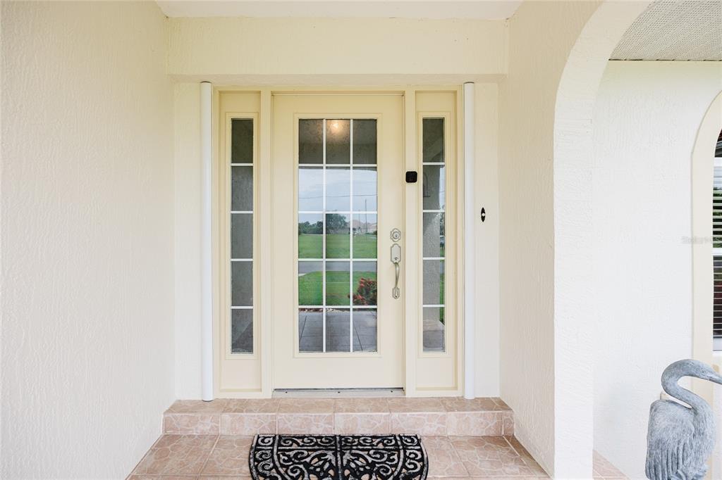 A cream-colored front door with glass panels and sidelights sits on a tiled porch — 24102 SANTA INEZ ROAD, PUNTA GORDA, FL