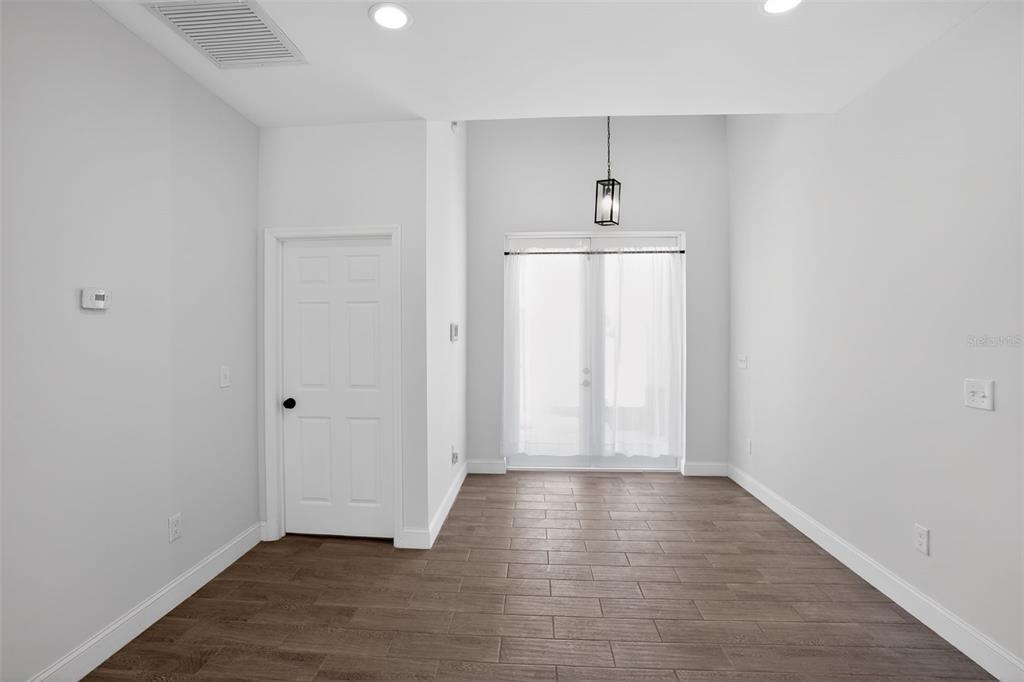 A room with light gray walls, wood-look tile flooring, a white door, and glass doors — 4630 GENE AVENUE N, LEHIGH ACRES, FL