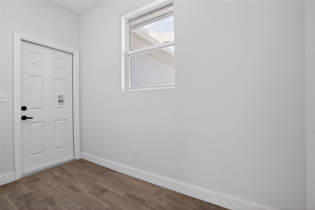 A room with a white door, a single window, and wood-look tile flooring — 4630 GENE AVENUE N, LEHIGH ACRES, FL