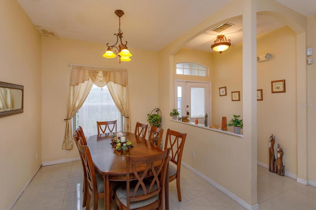 A dining room features a wooden table, six chairs, a chandelier, and tile flooring — 244 BALLYSHANNON DRIVE, DAVENPORT, FL