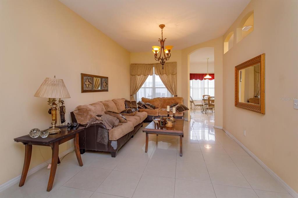 A living room features beige tile floors, a brown sofa, and a chandelier — 244 BALLYSHANNON DRIVE, DAVENPORT, FL