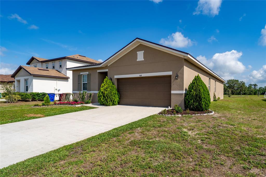 A tan single-story house with a two-car garage and a concrete driveway — 5610 WESTERN SUN DRIVE, ST CLOUD, FL