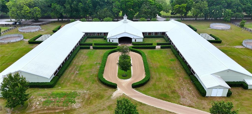 An aerial view shows a large U-shaped horse stable with a central driveway and paddocks — 19431 NE 17TH PLACE, WILLISTON, FL