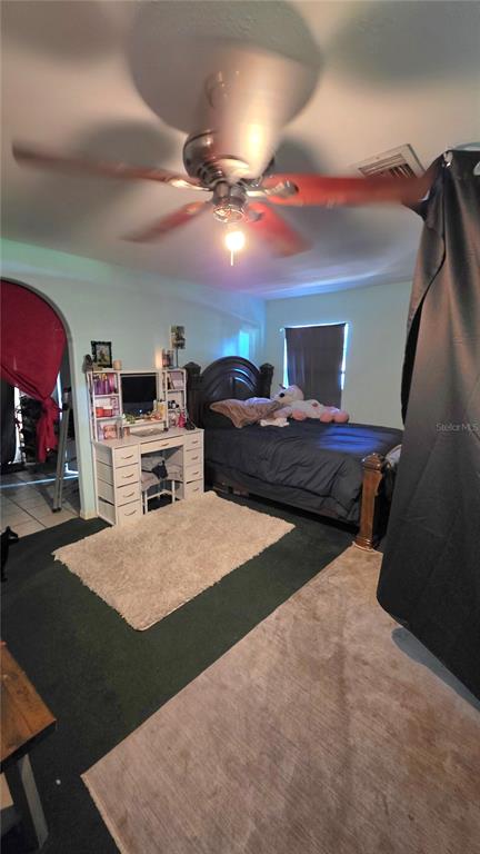 A bedroom features a dark bed, a white vanity, a ceiling fan, and two area rugs — 1808 ZIPPERER ROAD, BRADENTON, FL