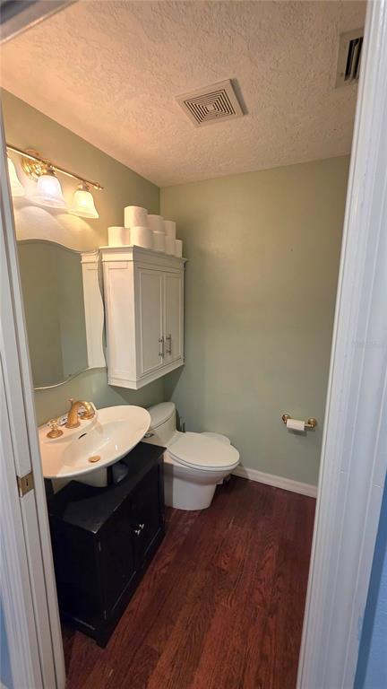 A small bathroom features a pedestal sink, a white wall cabinet, and a toilet — 1808 ZIPPERER ROAD, BRADENTON, FL