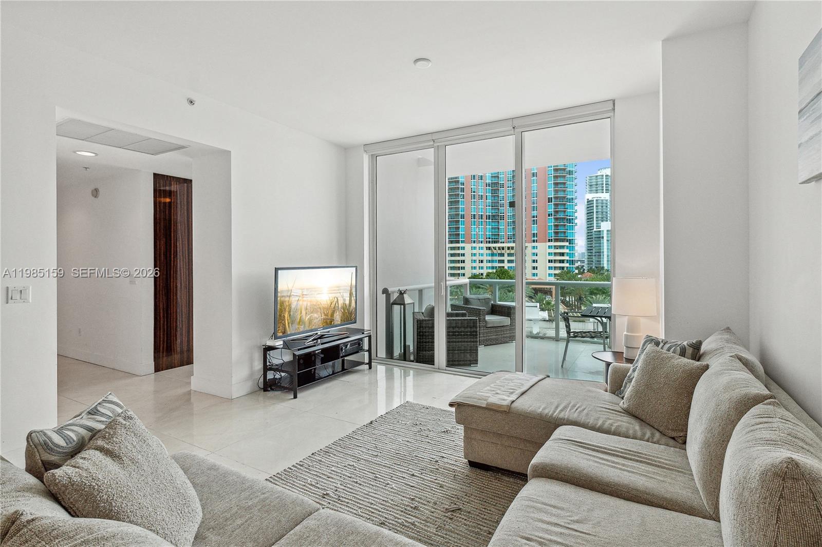 A living room features a sectional sofa, a television on a stand, and a balcony — 50 S Pointe Dr # 805, Miami Beach FL 33139, MIAMI BEACH, FL