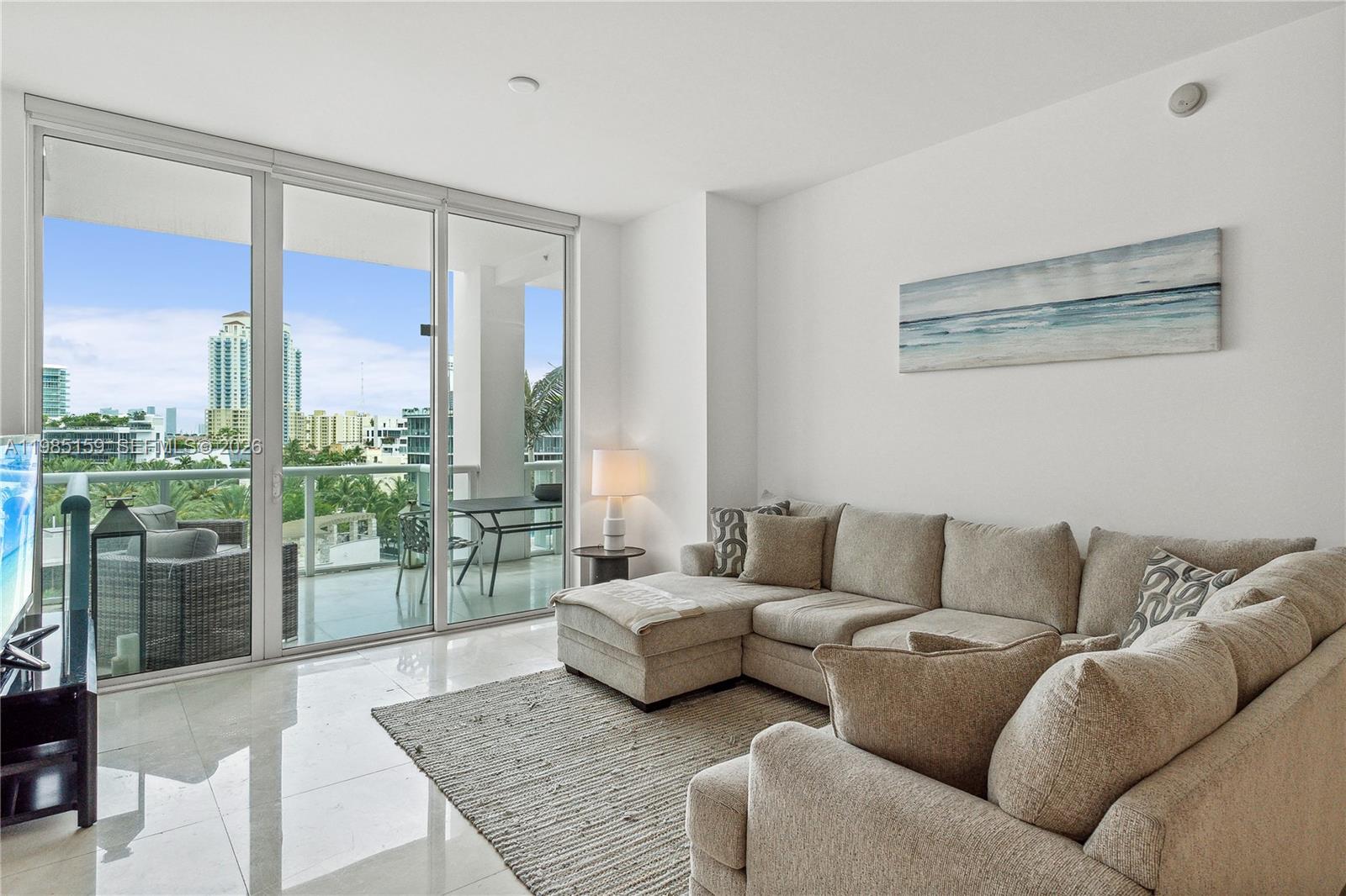 A living room features a beige sectional sofa, a textured rug, and a balcony view — 50 S Pointe Dr # 805, Miami Beach FL 33139, MIAMI BEACH, FL