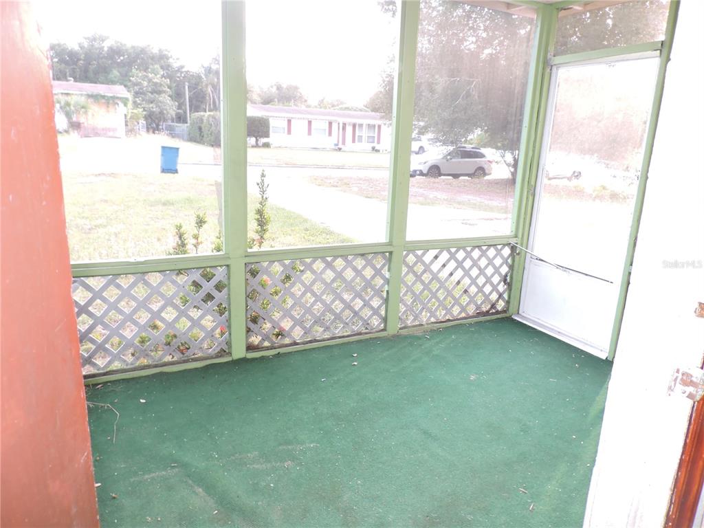 A screened-in porch features green carpeting, lattice panels, and a white door — 713 EUCLID AVENUE, LAKE WALES, FL