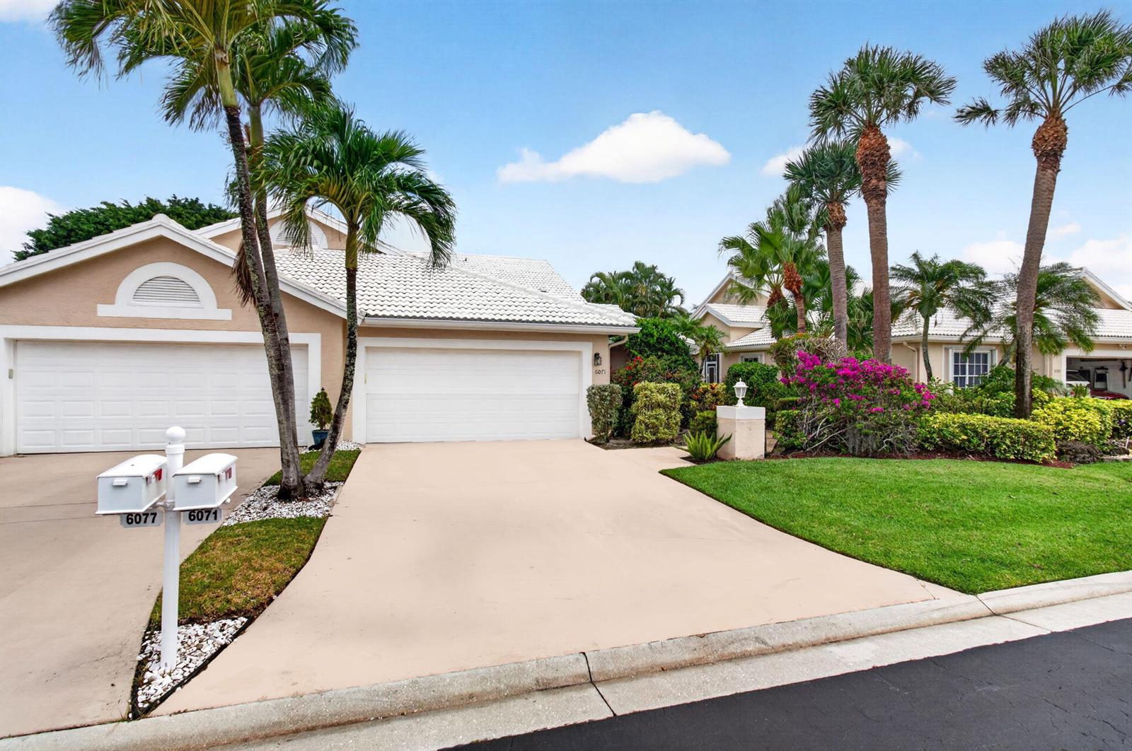 A tan single-story house features a two-car garage, a concrete driveway, and palm trees — 6071 Greenspointe Drive, Boynton Beach FL 33437, BOYNTON BEACH, FL