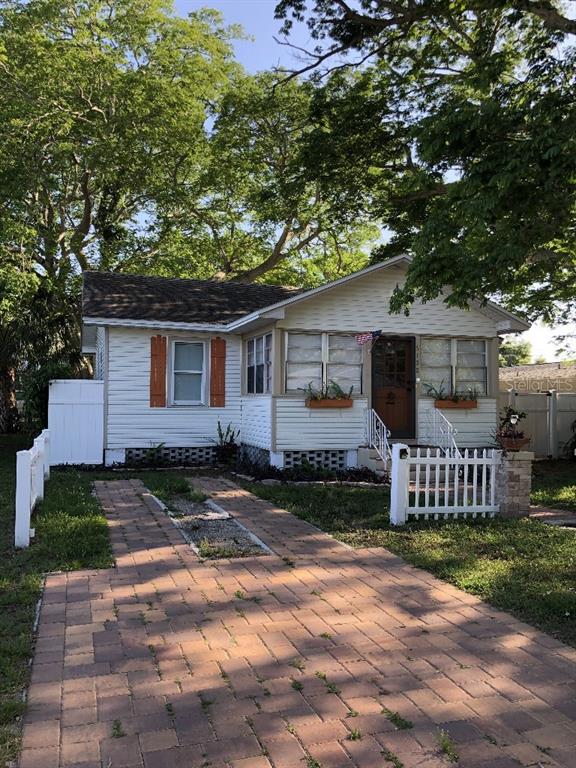 A single-story house with white siding, a brick driveway, and a white picket fence — 6100 FLORIDA AVENUE, NEW PORT RICHEY, FL