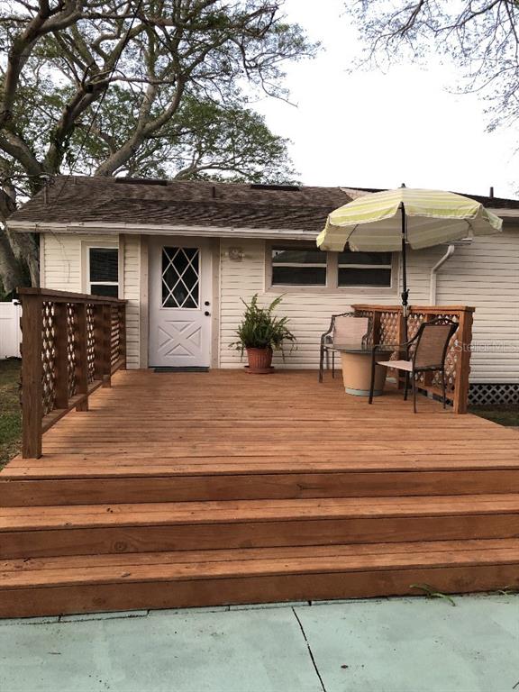 A wooden deck with stairs leads to the back entrance of a house with siding — 6100 FLORIDA AVENUE, NEW PORT RICHEY, FL