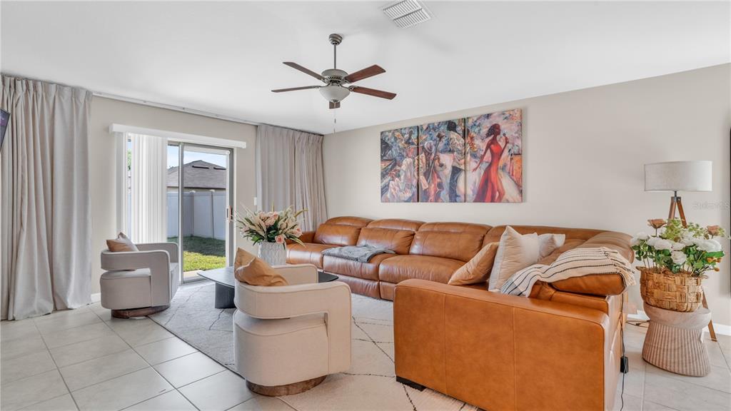 A living room features a tan leather sectional, two cream armchairs, and a sliding glass door — 1841 CRINKLE LEAF COURT, RUSKIN, FL