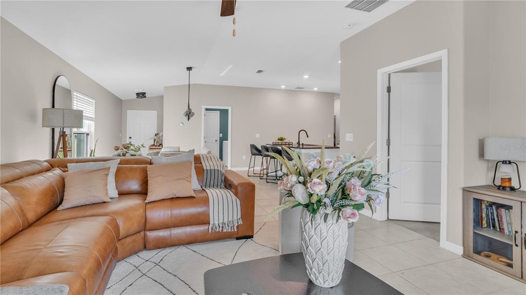 A living room with a tan leather sectional sofa, tile flooring, and an open kitchen — 1841 CRINKLE LEAF COURT, RUSKIN, FL
