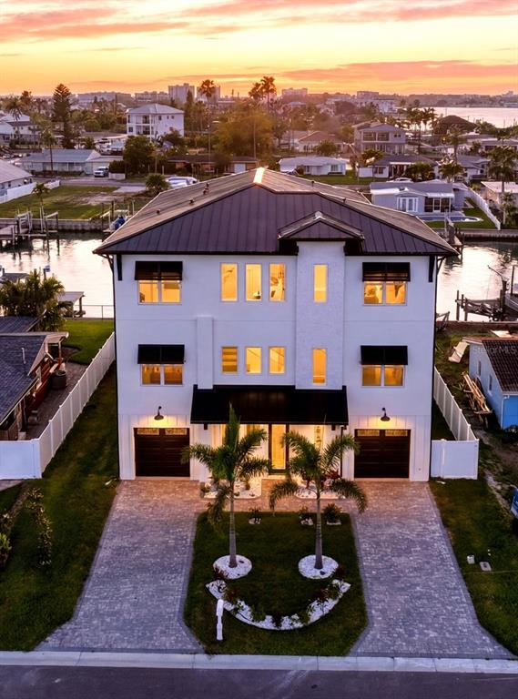 An aerial view of a three-story white house with a dark metal roof at sunset — 534 CRYSTAL DRIVE, MADEIRA BEACH, FL