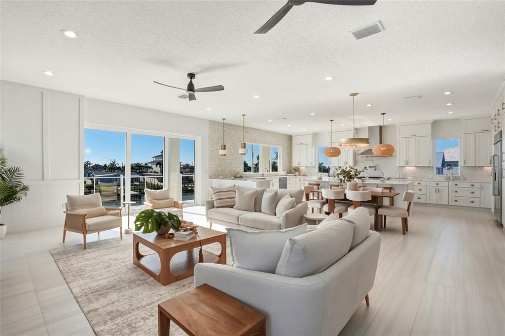 An open-concept living and dining area features white cabinetry, light tile floors, and waterfront views — 534 CRYSTAL DRIVE, MADEIRA BEACH, FL