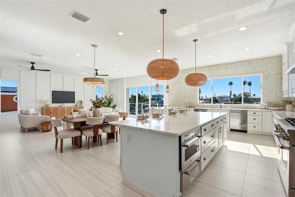 A bright, open-concept kitchen and dining area features a large island and modern light fixtures — 534 CRYSTAL DRIVE, MADEIRA BEACH, FL