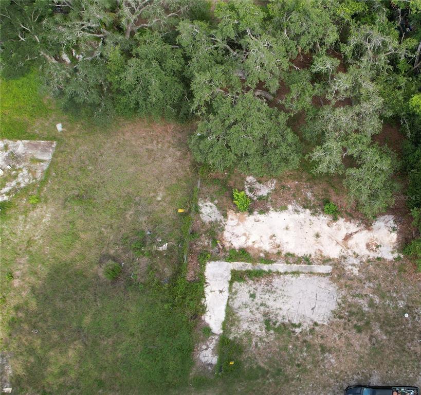 An aerial view of a vacant, partially cleared lot with concrete foundations and mature trees — 11406 POLO STREET, NEW PORT RICHEY, FL