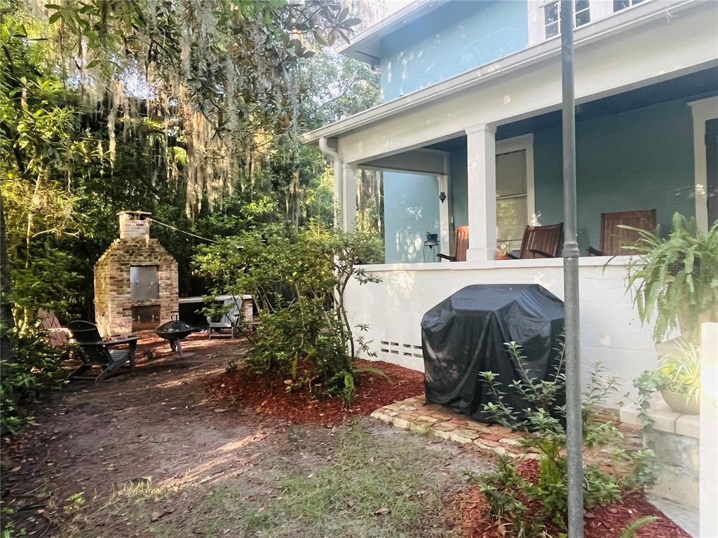 A blue house with a covered porch, outdoor grill, and brick fireplace in the yard — 1124 NW 4TH STREET NW, GAINESVILLE, FL