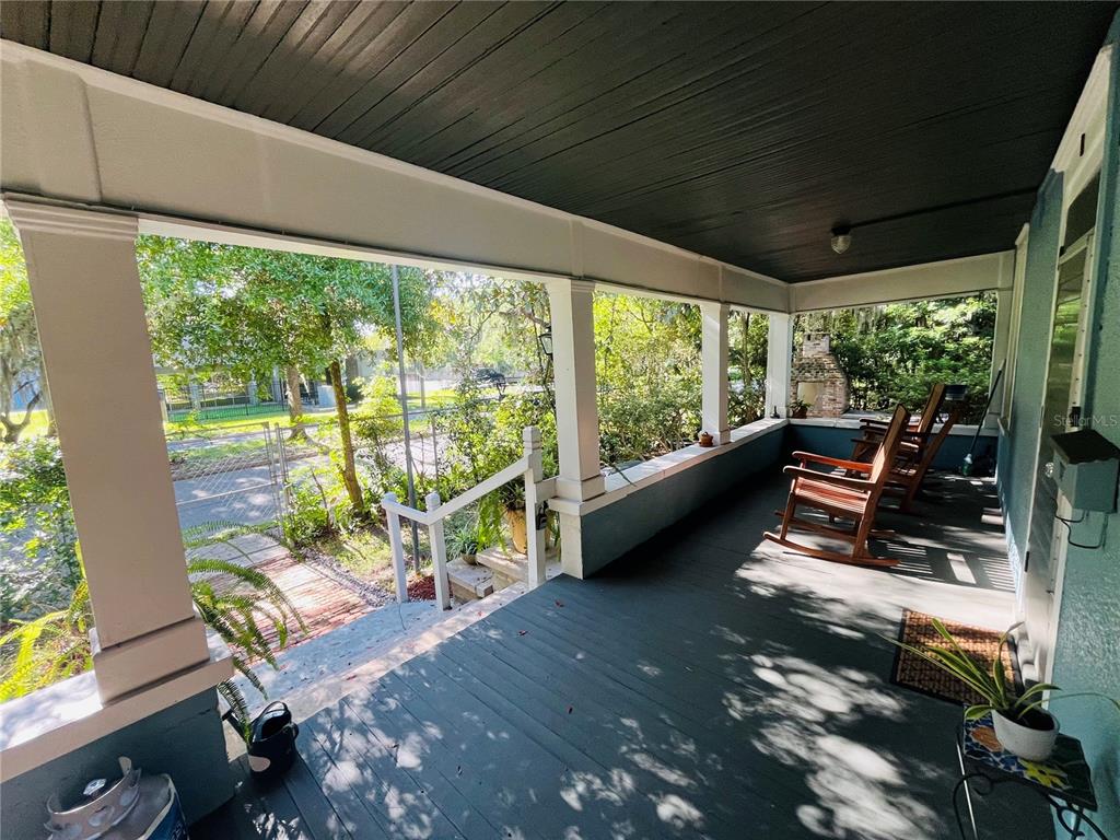 A covered front porch features dark painted wood flooring, white columns, and two wooden rocking chairs — 1124 NW 4TH STREET NW, GAINESVILLE, FL