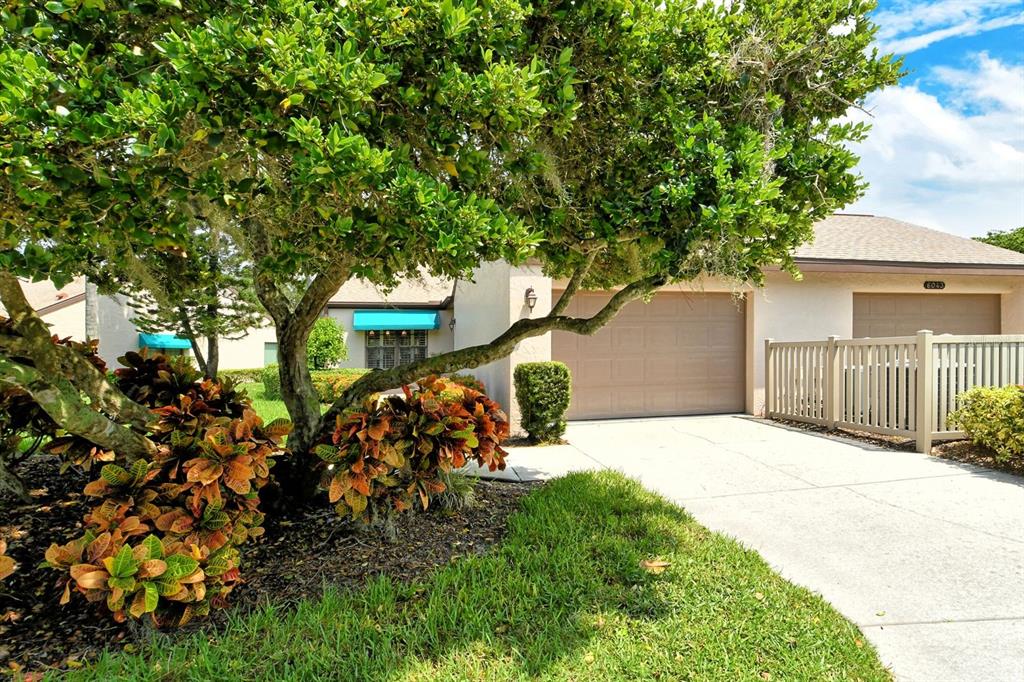 A single-story house with a beige exterior, a two-car garage, and a large shade tree — 6041 CLUBSIDE DRIVE UNIT 6041, SARASOTA, FL