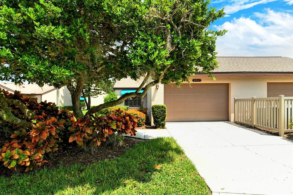 A single-story residential building with a tan garage, a concrete driveway, and a large tree — 6041 CLUBSIDE DRIVE UNIT 6041, SARASOTA, FL