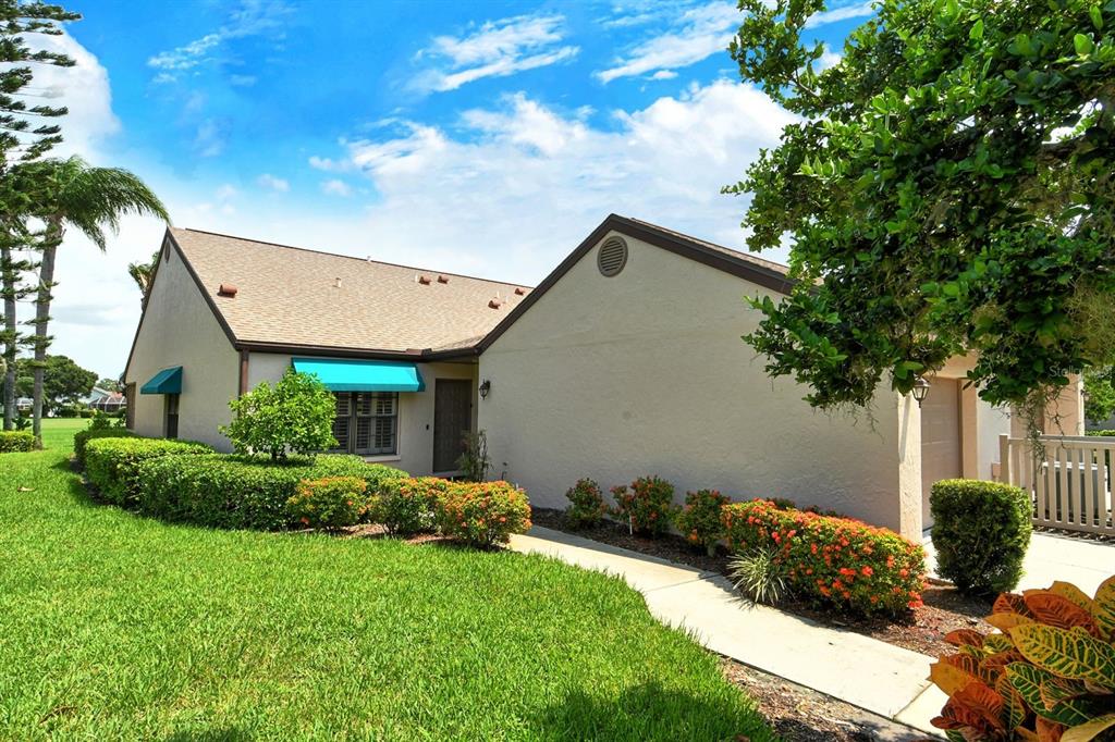 A single-story house with a beige exterior, a brown roof, and a landscaped front yard — 6041 CLUBSIDE DRIVE UNIT 6041, SARASOTA, FL