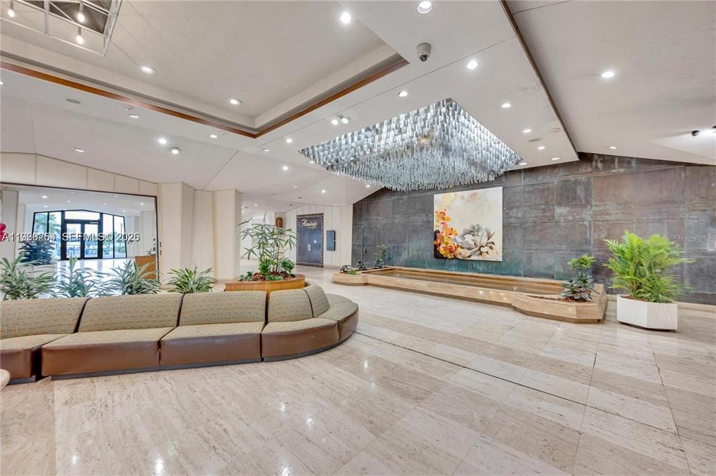 A spacious building lobby features a large crystal chandelier, a curved sofa, and a fountain — 999 BRICKELL BAY DRIVE UNIT 1202, MIAMI, FL