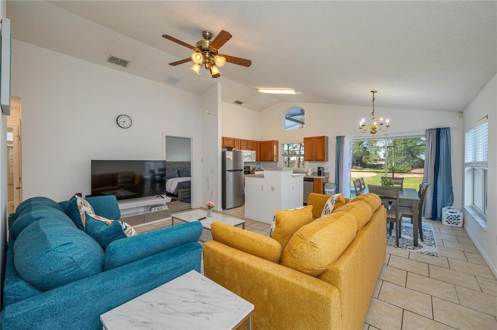 An open-concept living and dining area features a yellow sofa, blue sofa, and kitchen — 2660 HEMINGWAY AVENUE, HAINES CITY, FL