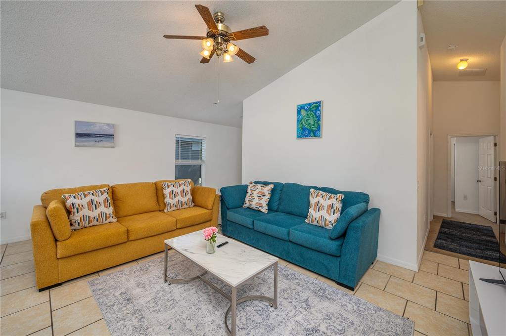 A living room features a yellow sofa, a blue sofa, and a marble-topped coffee table — 2660 HEMINGWAY AVENUE, HAINES CITY, FL